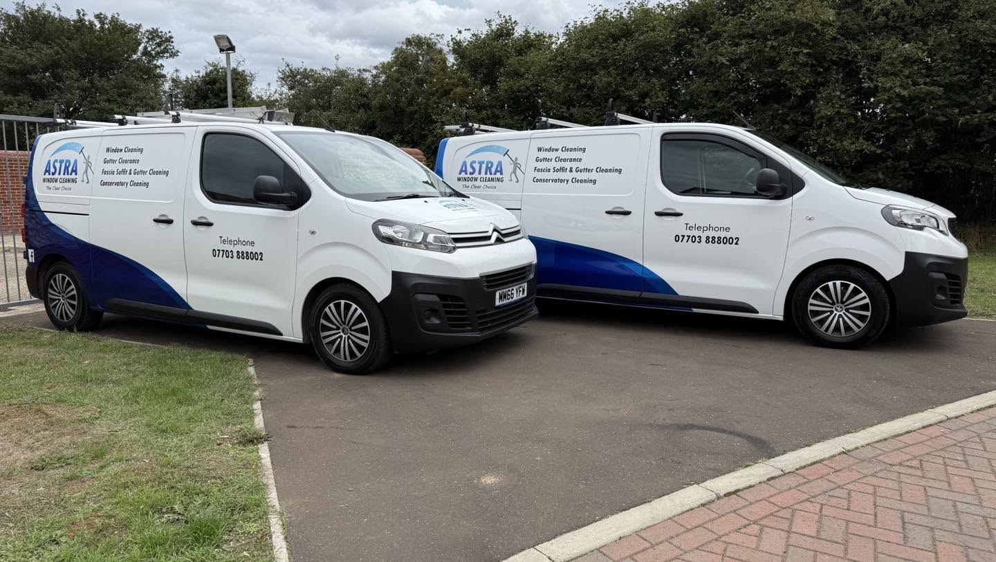 Two blue and white Astra Window Cleaning vans parked side by side